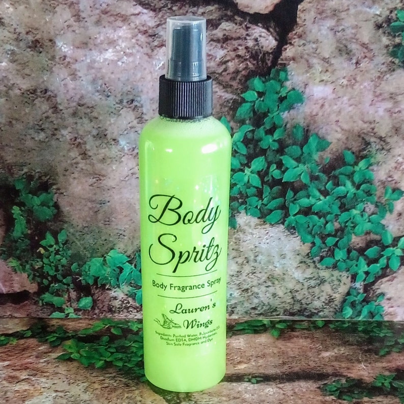 K&ouml;nnte beinhalten: Eine gr&uuml;ne Flasche K&ouml;rperspray mit schwarzem Spr&uuml;hkopf. Das Etikett lautet "Body Spritz Body Fragrance Spray Lauren's Wings".