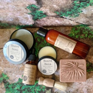 May include: A set of beard care products in brown glass bottles and jars with a brown and white label that says "Morning Wood". The products include beard wash, beard balm, beard oil, and shave soap. There is also a brown bar of soap with a leaf design and a wooden shaving brush.