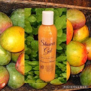 May include: A clear bottle of orange shower gel with a white label that reads "Shower Gel, Bath & Body Wash, Lauren's Wings". The bottle is surrounded by green leaves and ripe mangoes.