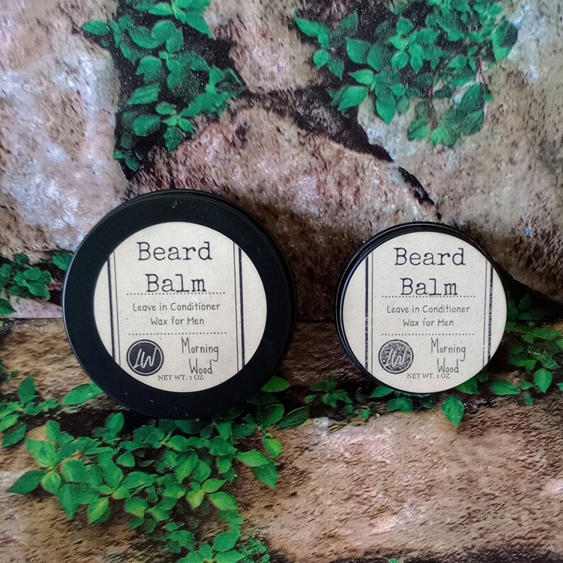 May include: Two round black tins with white labels. The labels read "Beard Balm Leave in Conditioner Wax for Men Morning Wood NET WT. 1 OZ".