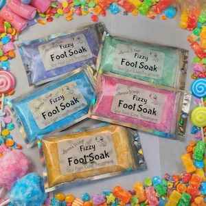 May include: Five rectangular pouches of fizzy foot soak spa foot care treatment in purple, green, blue, pink, and orange. Each clear plastic packet features a white label with the text Lauren's Wings Fizzy Foot Soak Spa Foot Care Treatment.