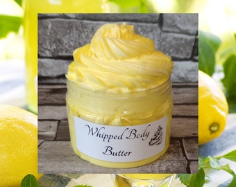 May include: A glass jar of yellow whipped body butter with a white label that reads "Whipped Body Butter". The jar is sitting on a white and green checkered surface.