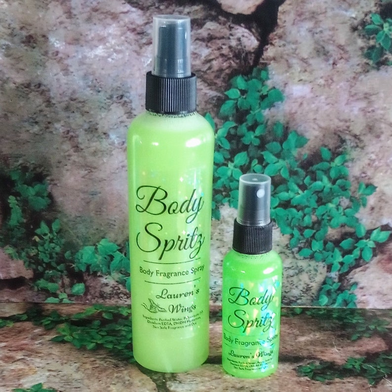 K&ouml;nnte beinhalten: Zwei gr&uuml;ne Glasflaschen mit schwarzen Spr&uuml;hk&ouml;pfen. Die gr&ouml;&szlig;ere Flasche hat ein Etikett mit der Aufschrift "Body Spritz Body Fragrance Spray Lauren's Wings". Die kleinere Flasche hat ein Etikett mit der Aufschrift "Body Spritz Body Fragrance Spray Lauren's Wings".