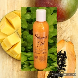 May include: A clear orange bottle of shower gel with a white lid and a label that reads "Shower Gel, Bath & Body Wash, Lauren's Wings". The bottle is sitting on a wooden surface with a mango and papaya fruit in the background.