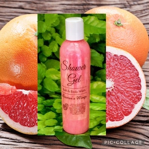 May include: A pink bottle of shower gel with the words "Shower Gel" and "Bath & Body Wash" on the label. The label also includes the text "Lauren's Wings". The bottle is sitting on a wooden surface with a grapefruit slice in the background.