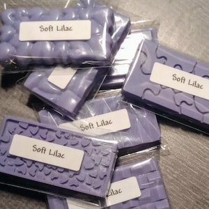 May include: Six individually packaged bars of purple scented wax melt with the text "Soft Lilac" on each label.