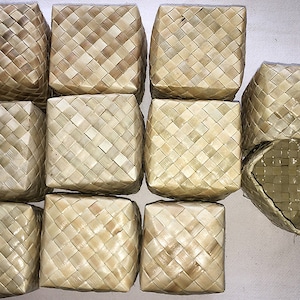 May include: Ten woven baskets made of natural materials, with a light brown color. The baskets are square and have a woven pattern.