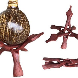 Pode incluir: Um recipiente artesanal de casca de coco com um suporte de madeira. A casca é marrom com raios dourados, e o suporte é de um marrom avermelhado profundo. O suporte é feito de peças de madeira interligadas.
