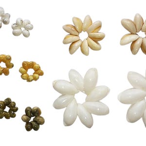 Może przedstawiać: Zestaw małych, białych, kremowych i brązowych muszelek ułożonych w kształcie kwiatów. Muszelki są różnej wielkości i kształtu i są ułożone w różnych wzorach.