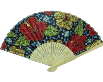 May include: A hand fan with a black background, featuring a vibrant floral pattern of red and yellow hibiscus flowers, green leaves, and blue accents. The fan's handle is made of light-colored wood.