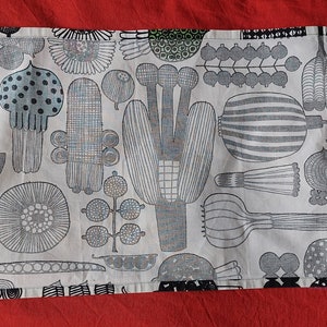 May include: A white tea towel with a black and gray pattern of stylized plants and flowers. The towel has a loop for hanging.