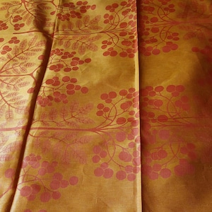 May include: A gold fabric with a red floral pattern. The fabric has a subtle sheen and a textured surface.