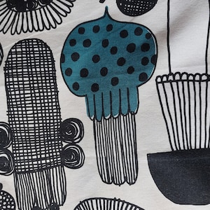 May include: Black and white fabric with a repeating pattern of stylized plants and flowers. The fabric features a teal blue flower with black polka dots.