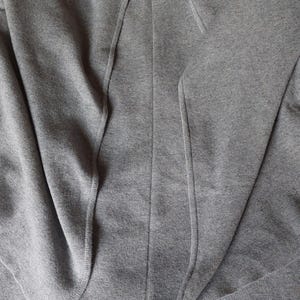 May include: A gray knitted cardigan with a long, open front and a relaxed fit.