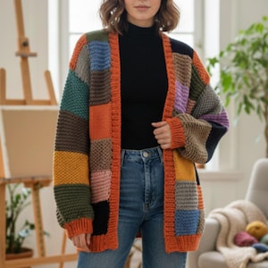 May include: A patchwork knit cardigan in a variety of colors, including orange, blue, green, and yellow. The cardigan has a chunky knit texture and a long, open design. The model is wearing a black turtleneck and blue jeans.