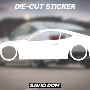 May include: White die-cut sticker of a car silhouette. The sticker says "DIE-CUT STICKER" at the top and "SAVIO DOM" at the bottom.