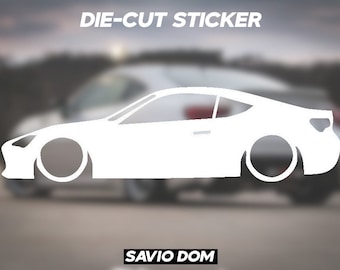 May include: White die-cut sticker of a car silhouette. The sticker says "DIE-CUT STICKER" at the top and "SAVIO DOM" at the bottom.