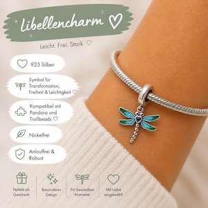 Könnte beinhalten: Ein silberner Libellen-Charm mit blau-grünen Emaille-Details, befestigt an einem silbernen Armband. Der Charm ist ein Symbol für Transformation, Freiheit und Leichtigkeit. Der Text auf dem Bild lautet "Libellencharm".