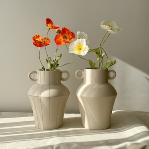 There are two vases. One is a plain cream color. The other one is cream colored and has a striped pattern.