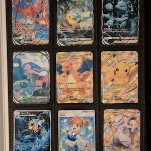 K&ouml;nnte beinhalten: Eine Sammlung von neun Pok&eacute;mon-Sammelkarten in einem Ordner. Die Karten zeigen verschiedene Charaktere, darunter Glurak, Pikachu und Mewtu, mit leuchtenden Farben und holografischen Effekten. Die Karten befinden sich in Schutzh&uuml;llen.