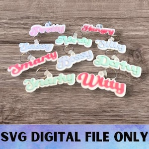 May include: A set of 12 colorful keychains with different names written on them. The names include "Pretty", "Hungry", "Nerdy", "Bossy", "Smarty", "Witty", "Sassy", "Silly", "Dorky", and "Darty".