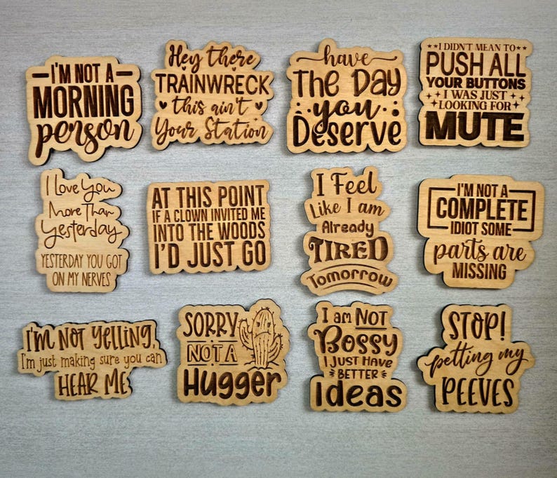 Puede incluir: Recortes de madera con frases humor&iacute;sticas grabadas, como "No soy una persona de la ma&ntilde;ana" y "Lo siento, no soy de abrazos". El texto marr&oacute;n oscuro contrasta con la madera marr&oacute;n claro. Ideal para regalos.