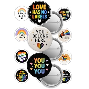 以下が含まれることがあります： Love Has No Labels、You Belong Here、You You You、Proud Ally、Safe Space、Human Kind、Support Equality Love、Not Just An Allyなどのテキストと虹色のデザインが施された、円形のピンバッジのコレクション。