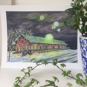 Puede incluir: Una pintura de acuarela de un edificio de ladrillo rojo con un techo verde, sobre un fondo de cielo nocturno oscuro con orbes verdes brillantes. El edificio tiene una plataforma de madera y está rodeado de nieve. La pintura está enmarcada en blanco.