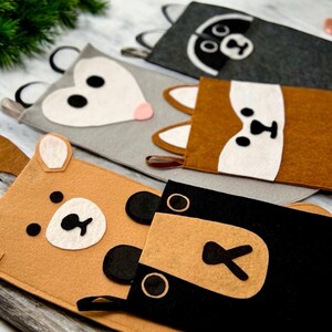 May include: Five felt stocking holders with animal faces. The holders are brown, gray, black, and white with felt appliques of a raccoon, a fox, a bear, a deer, and a possum.