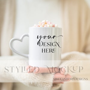 Mockup della tazza della maniglia a forma di cuore della donna, modello di tazza a forma di cuore vuoto, modello di tazza da caffè bianco accogliente, mockup della tazza di smalto bianco vuoto