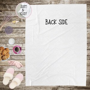 May include: White, soft and cozy blanket with the text "BACK SIDE" printed in black on the front.