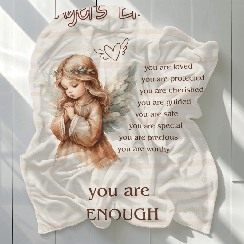 May include: A white blanket with a watercolor illustration of an angel with wings and a heart above her head. The blanket has the text "You are loved, You are protected, You are cherished, You are guided, You are safe, You are special, You are precious, You are worthy, You are ENOUGH" printed on it.