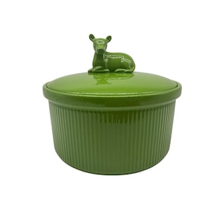 May include: A round, lime green ceramic lidded container with a vertical ribbed texture on the exterior. The lid features a sculpted, three-dimensional figure of a small, resting deer or fawn in a matching glossy green finish on the top center.