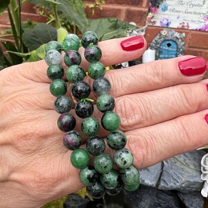 May include: A green and black gemstone bracelet with multiple strands of beads. The bracelet is made of round, smooth beads with a speckled pattern.