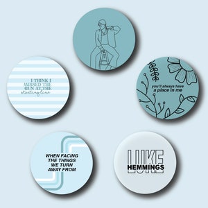 Può includere: Cinque bottoni rotondi blu e bianchi con testo nero e disegni a linea. I bottoni presentano testi della band "Like Hemmings". I testi sono: "I think I missed the gun at the starting line", "you'll always have a place in me", "When facing the things we turn away from", e "Like Hemmings".