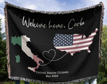 May include: Black woven throw blanket with white fringe. Features a map of the United States with an American flag design and a map of Italy. Text reads "Welcome home, Carla", "United States Citizen", and "May 2026".