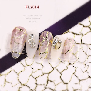 Puede incluir: Cinco puntas de uñas rosas y blancas con detalles de lámina dorada y pedrería. Las puntas de uñas están dispuestas en fila sobre una superficie blanca con un patrón de craquelado dorado.