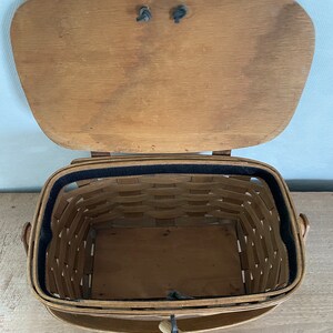 May include: A wooden basket with a hinged lid and a black fabric lining. The basket has two handles and a wooden latch.