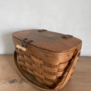 May include: A brown wooden picnic basket with a woven design and a hinged lid. The basket has a single handle and metal clasps.