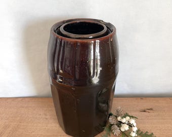Könnte beinhalten: Eine dunkelbraune, glasierte Keramikvase mit rundem Korpus und leicht ausgestelltem oberen Rand. Die Vase hat ein rustikales, vintage-mäßiges Aussehen.