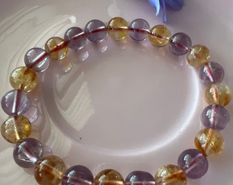 May include: A bracelet made of alternating purple and yellow beads. The beads are round and have a smooth, polished finish.