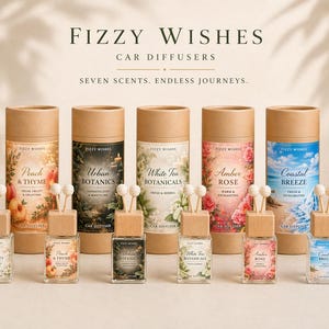 May include: A selection of Fizzy Wishes car diffusers, showcasing seven fragrances. The range includes Ylang Serenity, Peach & Thyme, Urban Botanics, White Tea Botanicals, Amber Rose, Coastal Breeze, and Green Tea & Lemongrass. Each diffuser is in a glass bottle with a wooden top.