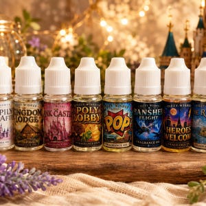 May include: Eight small clear plastic bottles of Fizzy Wishes fragrance oil with white dropper caps. Labels feature unique designs and text including Happily Ever After, Kingdom Lodge, Pink Castle, Poly Bobby, Pop, Banshee Flight, Heroes Welcome, and The Riviera.