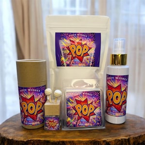 May include: A selection of Fizz Wishes products with a retro "POP" design. The items include a car diffuser, wax melt, room spray, and a bag of product. The packaging features a vibrant red, yellow, and purple color scheme with the text "FIZZY WISHES 50s POP 1989".