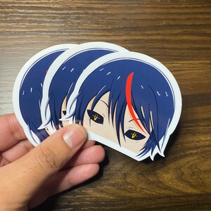 K&ouml;nnte beinhalten: Drei wei&szlig;e Aufkleber mit einem schwarzen und blauen Anime-Charakter mit gelben Augen. Der Charakter hat einen roten Streifen im Haar.