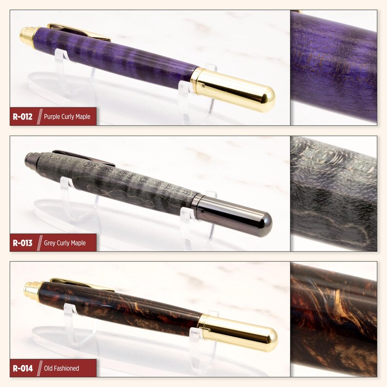 May include: Three wooden pens with different wood grain patterns and finishes. The pens are displayed on white stands. The first pen is purple with gold accents, the second is gray with black accents, and the third is brown with gold accents. The pens are labeled with their corresponding wood types: Purple Curly Maple, Grey Curly Maple, and Old Fashioned.