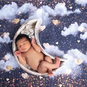 以下が含まれることがあります： 白い三日月型の小道具の中で、新生児が穏やかに眠っています。赤ちゃんは柔らかい白い毛布の上に横たわり、星空、雲、ハート型の装飾を背景にしています。全体的なシーンは、静けさと新たな始まりを連想させます。