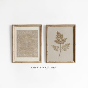 Può includere: Due stampe incorniciate di arte murale. Una presenta un disegno di tappeto beige, l'altra una pianta pressata. Entrambe sono in cornici dorate. Il testo "EMRE'S WALL ART" è sotto.