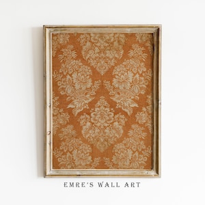 May include: A rectangular wall art print in a light-colored wooden frame featuring a repeating damask pattern in shades of burnt orange and cream. The design consists of symmetrical floral and leaf motifs arranged in a vertical, ornate layout.