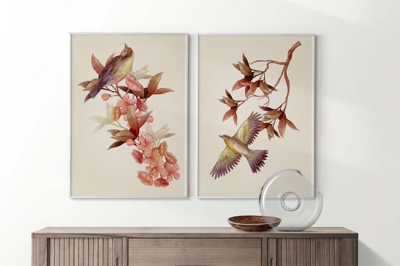 May include: Two framed watercolor paintings of birds perched on branches with pink flowers. The birds are brown and yellow with a light background.